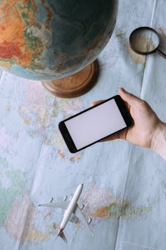 A globe, smartphone, and toy plane on a world map symbolize travel and exploration.