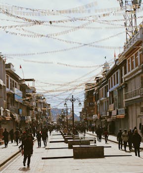 A lively urban street in India with people walking under strings of flags, showcasing daily life.