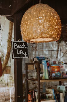 A warm and inviting display at a beach shop with a glowing lantern and travel magazines.