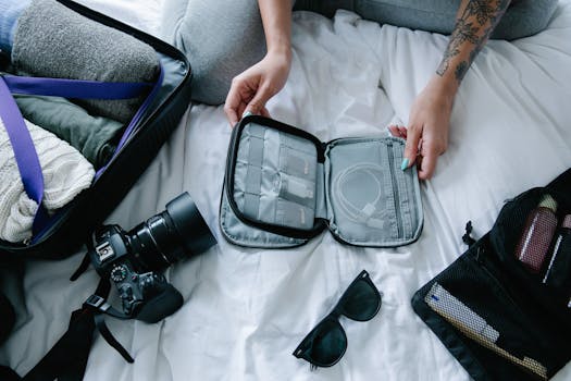 Traveler organizing essentials including a camera and packing cubes on a hotel bed.