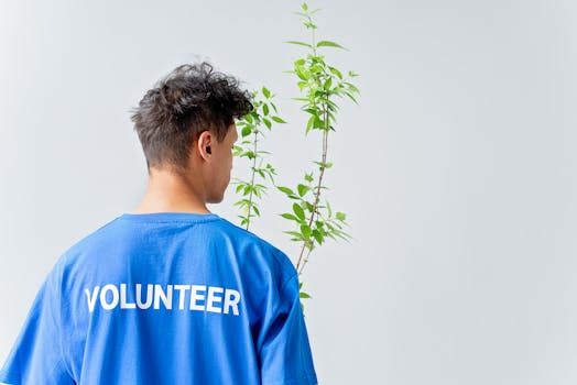 Young volunteer in blue shirt nurturing plant, symbolizing eco-friendly initiatives.